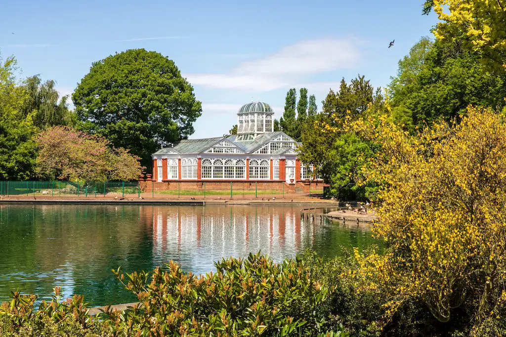 A scenic park in Wolverhampton, England, featuring a large lake surrounded by lush greenery and a Victorian-style conservatory. West Park has been a beloved local spot for bike rides, relaxation, and feeding the ducks since its creation.