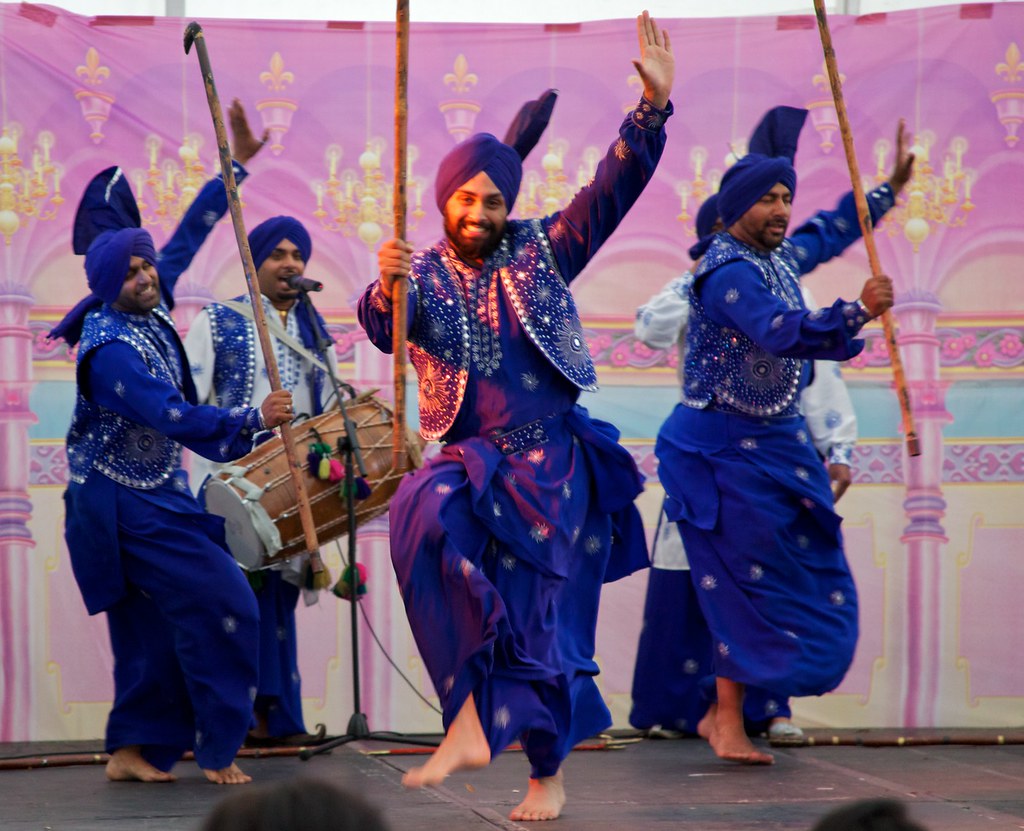 Punjabi dancers in bright purple attire performing Bhangra style dance at Birmingham Mela Festival, England
