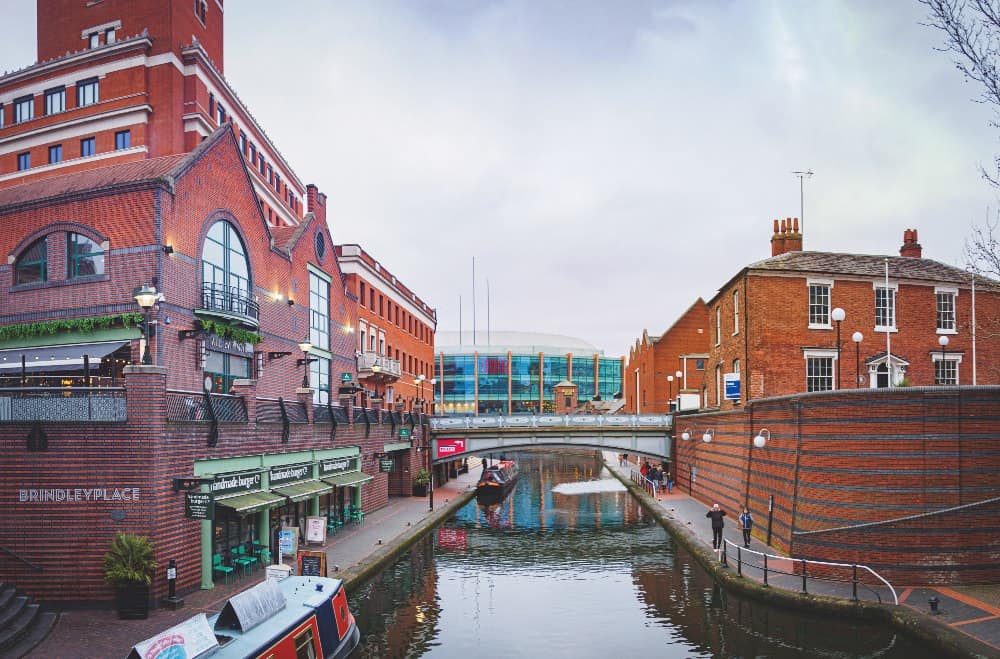 view of a canal between redbrick buildings in the centre of birmingham city, england
