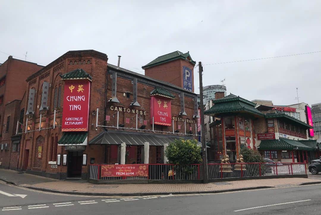 chinese style redbrick buildings with green rooftops and red signs at chinatown in birmingham, england