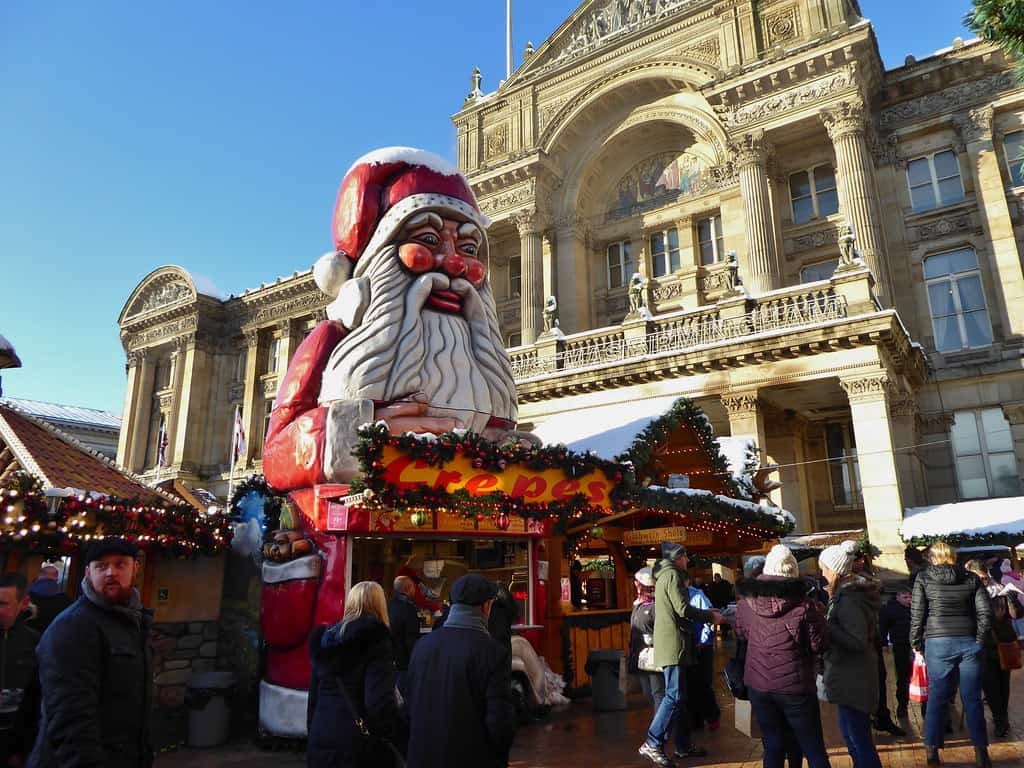 large santa statue behind festive wooden huts at the birmingham frankfurt christmas markets in birmingham city centre.