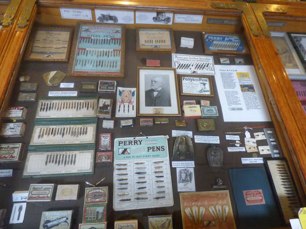 close up view of a collection of pen tips and nibs as well as other collectibles in a glass display case