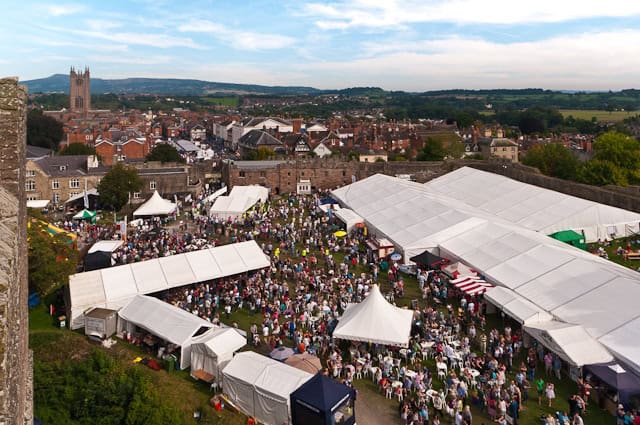 aerial view of the ludlow food festival market stalls packed with visitors with ludlow church and town visible in the distance