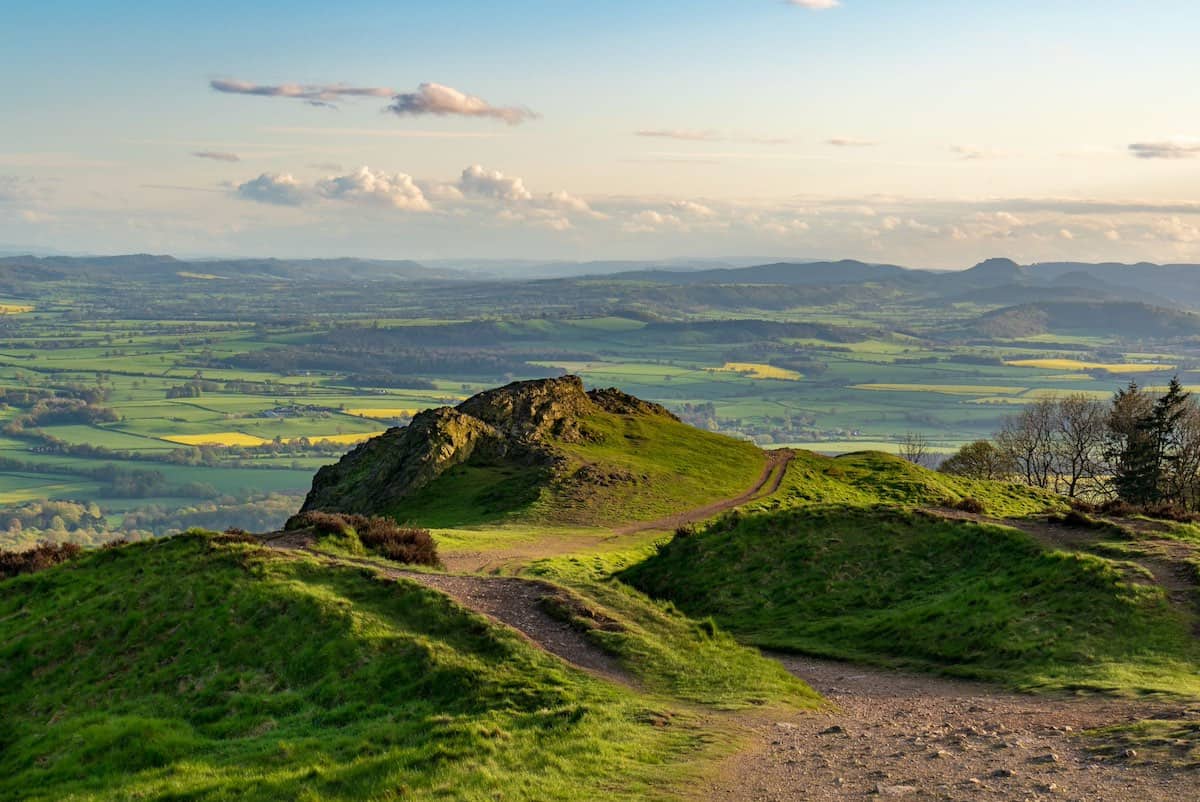 small hills on top of the wrekin, with dirt tracks and trails zigzagging over the hills, and aerial views of the vast countryside in the distance