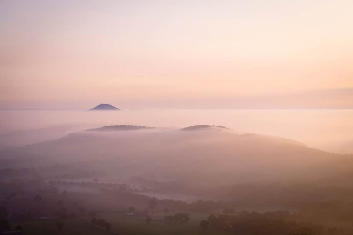 sunrise mist covering the hills of shropshire and the wrekin, with the wrekin's peak visible just above the mist