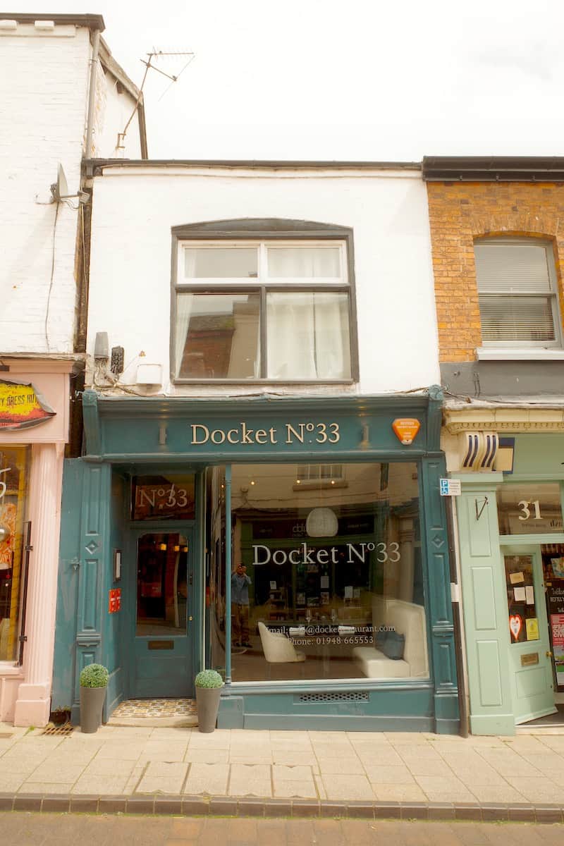 narrow, aquamarine coloured restaurant exterior with large glass window and sign across the top saying Docket No33