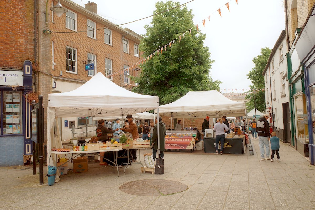white marquee tents on a street market with produce on sale