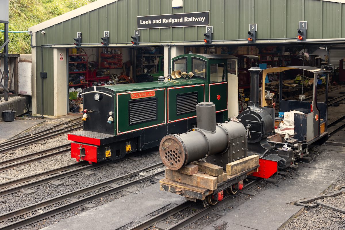 Leek and Rudyard Railway maintenance depot showing green and black vintage narrow gauge locomotives and workshop bays numbered 1-6 with signal lights mounted above each bay.
