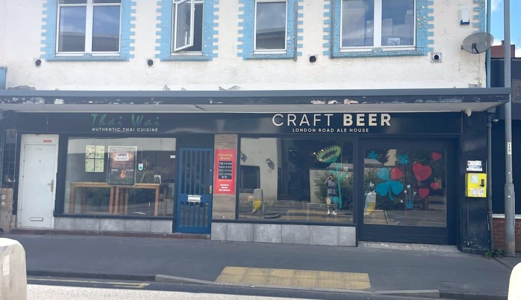 A street-level view of two adjacent businesses - a Thai restaurant with "Authentic Thai Cuisine" signage on the left, and the "Craft Beer London Road Ale House" on the right, both housed in a building with blue-trimmed windows above.