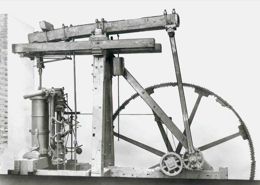 black and white photo of an early steam engine by James Watt and Matthew Boulton, showing the iconic circular and pump mechanisms.