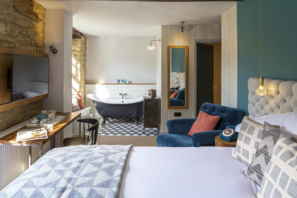 A modern, walk-in elegant bathroom at The Old Stocks Inn, viewed through a doorway from the stylish bedroom, showcasing a stand alone bathtub