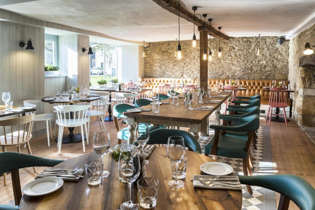 The vibrant dining room at The Old Stocks Inn, featuring colourful upholstered banquettes, contemporary artwork, and a lively, welcoming atmosphere.