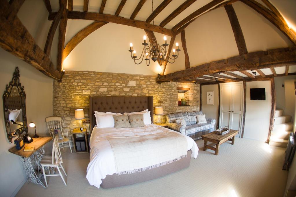 The historic bedroom facade with king size bed in the middle of the room, at The Porch House in Stow-on-the-Wold, England's oldest inn, showing its characteristic honey-coloured stonework, timber beams, and traditional entrance.
