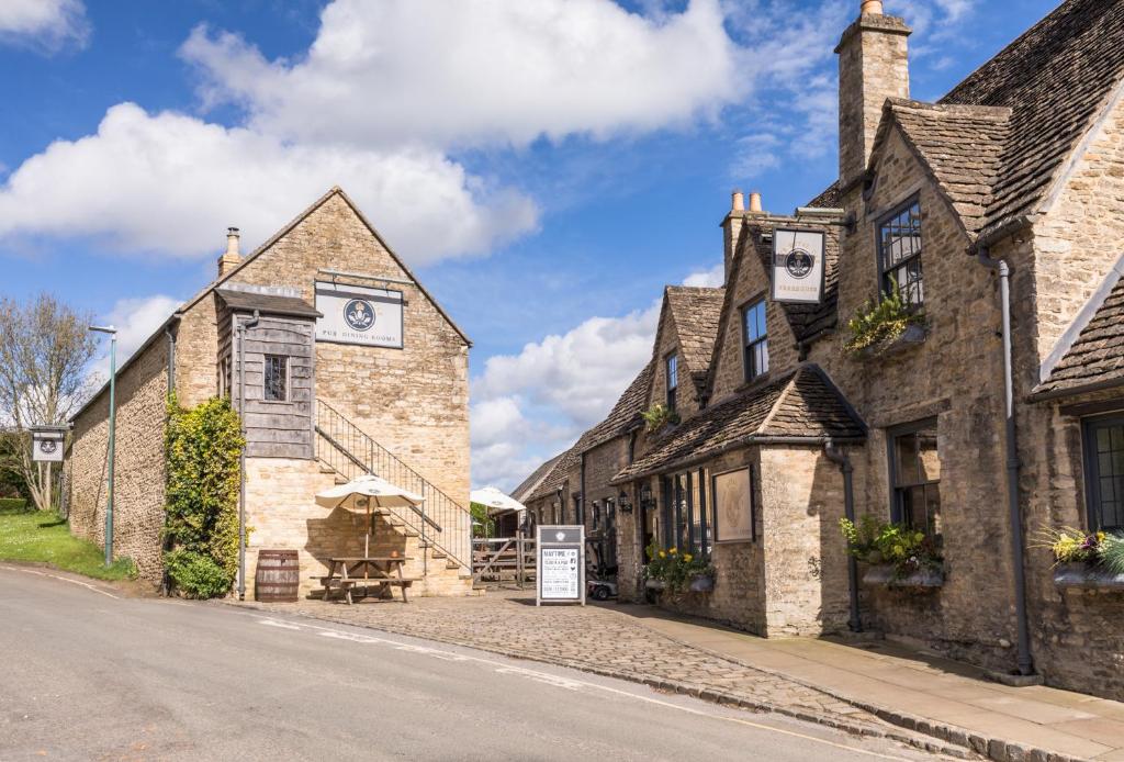 the royal oak hotel in Tetbury, a honey-coloured, medieval brick countryside cottage on a sloping hill with white signs outside