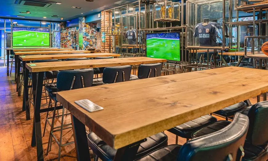 sky blue tavern interior showing wooden tables and large tv screens showing a live football match