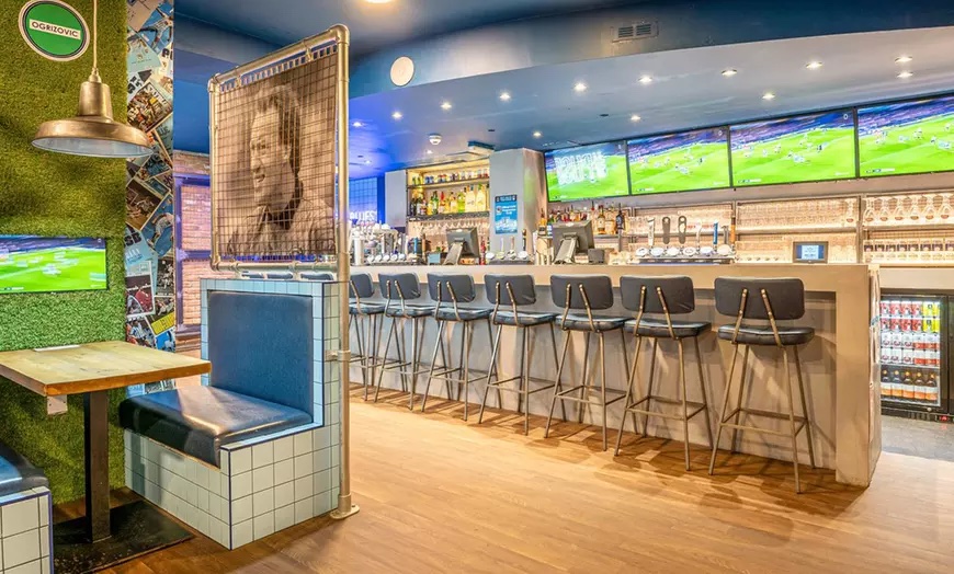 sky blue tavern with football memorabilia decor, high chairs and many tv screens all showing the same live football match.