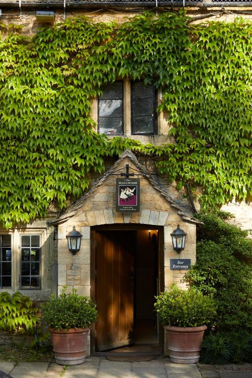 The charming main entrance of Slaughter's Inn, with its stone doorway framed by lush, green creeping foliage covering the walls.